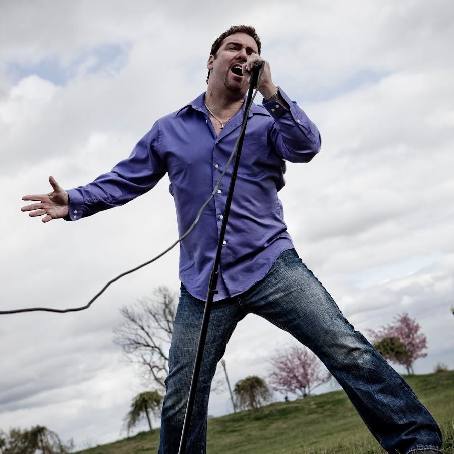 A man singing into a microphone in a field.